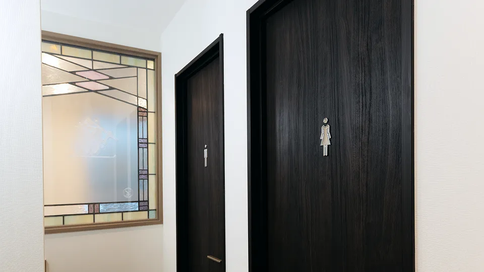 落ち着いた雰囲気の女性用トイレ。ダークな木目のドアが、静寂を誘います。