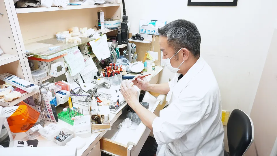 院内技工所で、精密な作業に集中する技師の姿。