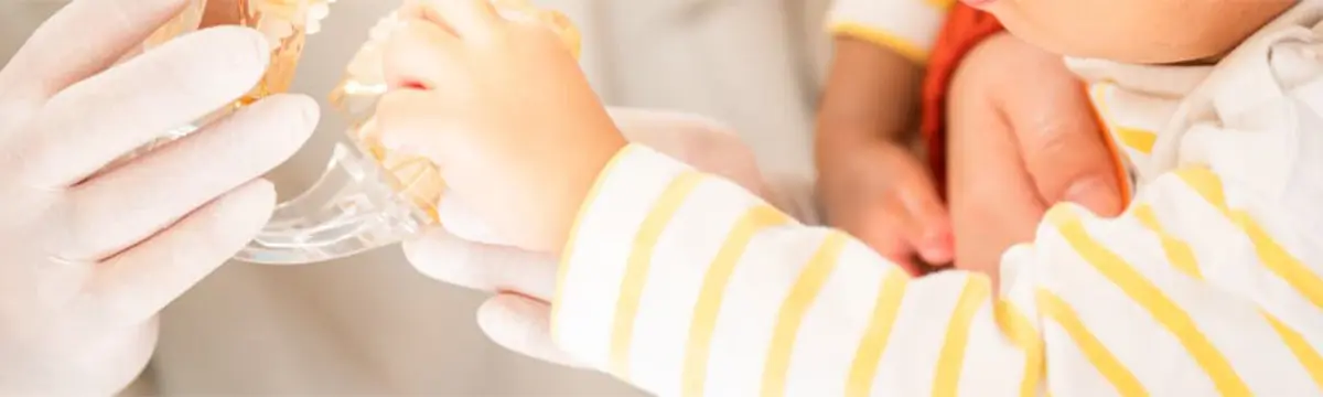 乳幼児が歯科スタッフと一緒に歯の模型に触れている様子。歯科医院に慣れさせるためのコミュニケーションの一場面。
