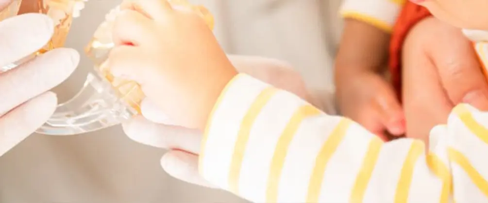 乳幼児が歯科スタッフと一緒に歯の模型に触れている様子。歯科医院に慣れさせるためのコミュニケーションの一場面。